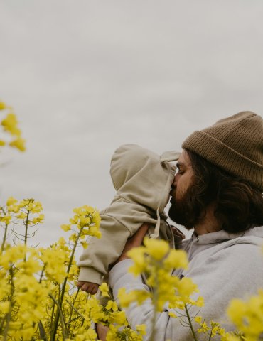 a man and woman kissing in a field of yellow flowers